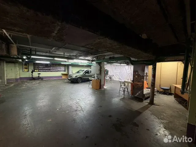 Тёмное изношенное помещение автосервиса с открытыми коммуникациями и старым полом